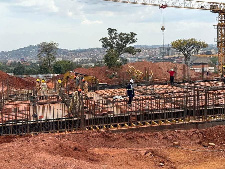 Reinforced concrete foundation and slab works, with excavator, tower crane and clay hollow blocks on site.