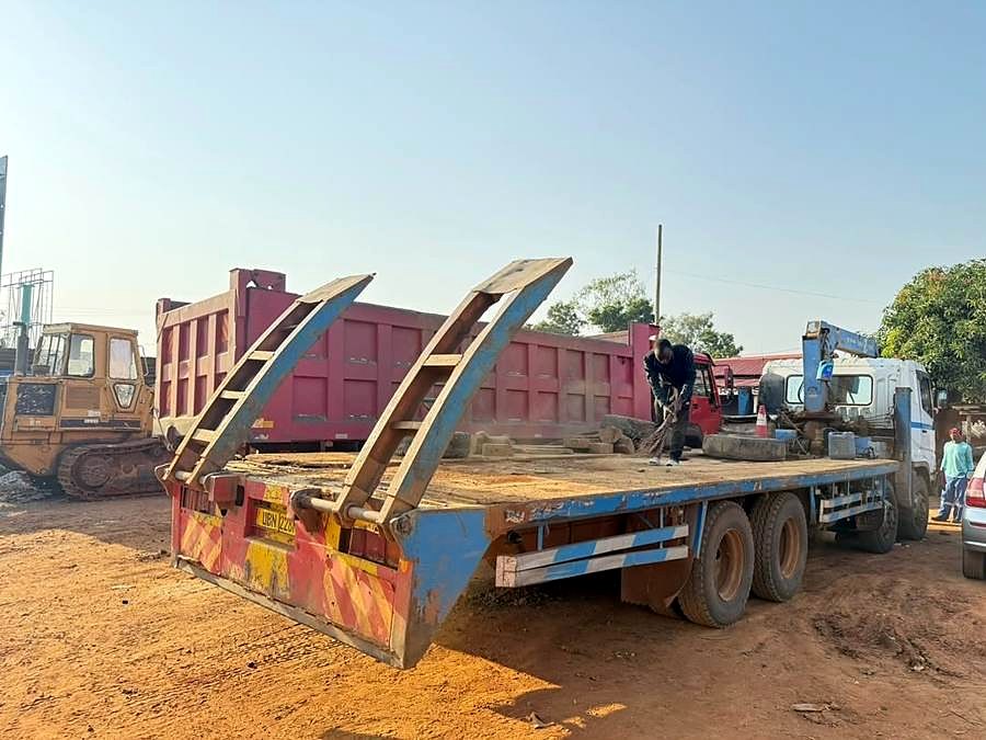 Flatbed truck with loading ramps on a site.