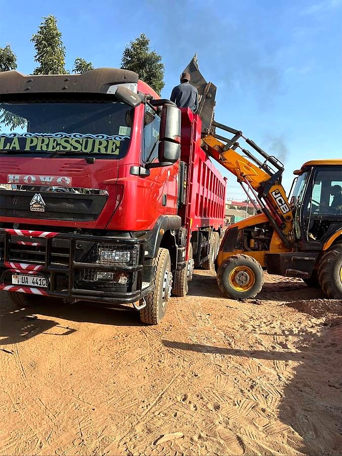 Sala Pressure tipper beside a backhoe loader on a sandy site.